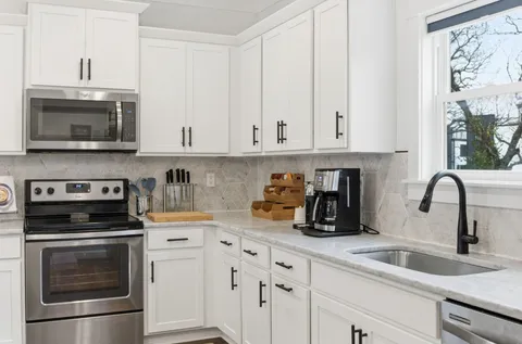 a kitchen with stainless steel appliances kitchen island granite countertop a sink a stove a refrigerator and cabinets