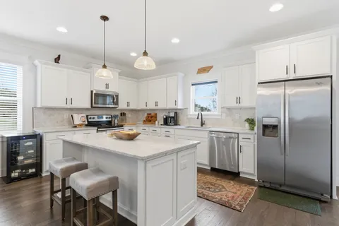 a kitchen with stainless steel appliances granite countertop a sink a stove a refrigerator and white cabinets