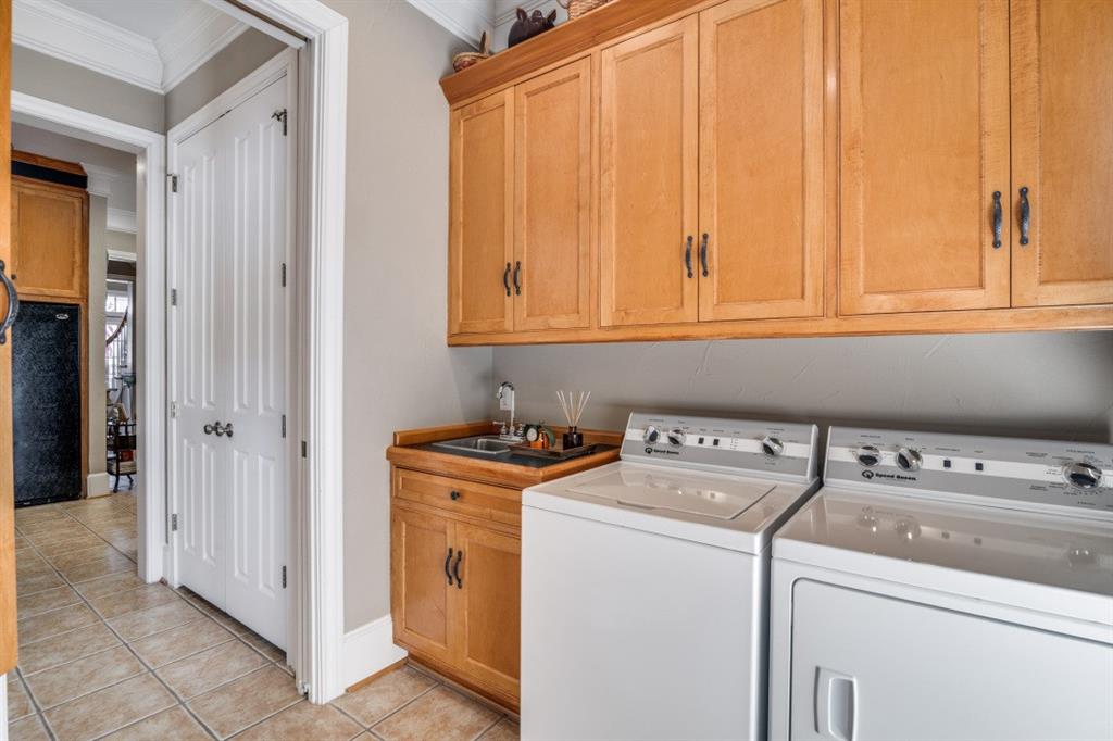 8 Griffith Court Terrell, TX 75160 - Photo 11 of 25 Laundry room featuring cabinet space, ornamental molding, washer and dryer, light tile patterned flooring, and a built-in desk and cabinet