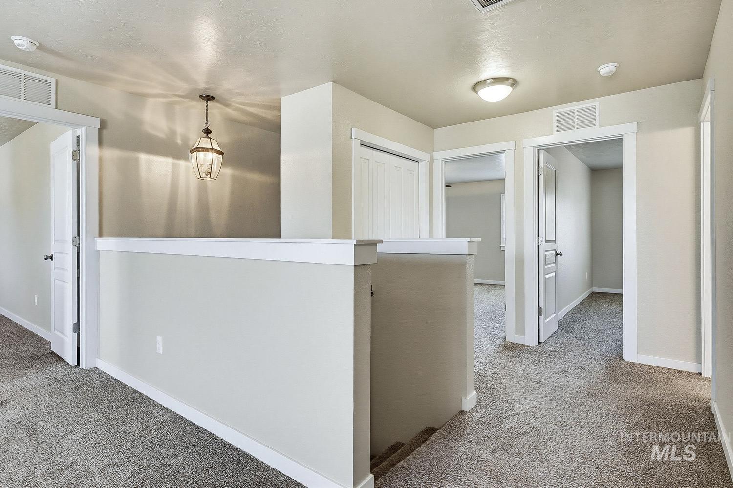 846 North Hidden View Way Star, ID 83669 - Photo 26 of 49 Upper-level landing featuring a hanging pendant light, neutral wall colors, white trim, and light gray carpet flooring