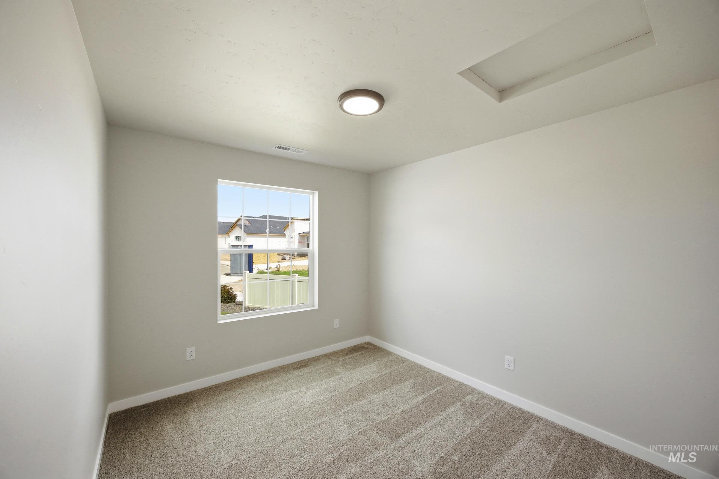 14044 Shiny Spruce Street Caldwell, ID 83607 - Photo 10 of 24 Neutral-toned room featuring a single window, recessed ceiling detail, and a modern flush-mount light fixture