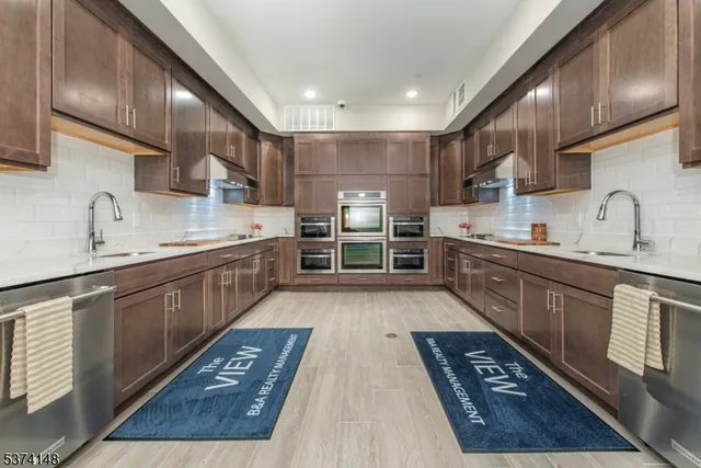 a large kitchen with stainless steel appliances granite countertop a large stove a sink dishwasher and cabinets with wooden floor