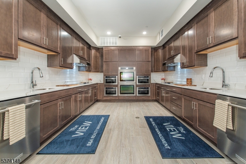 10 Kingsbridge Road, Unit 207 Fairfield, NJ 07004 - Photo 12 of 15 a large kitchen with stainless steel appliances granite countertop a large stove a sink dishwasher and cabinets with wooden floor