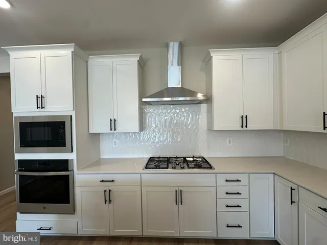 a kitchen with stainless steel appliances a kitchen island a stove a refrigerator a sink and wooden floor