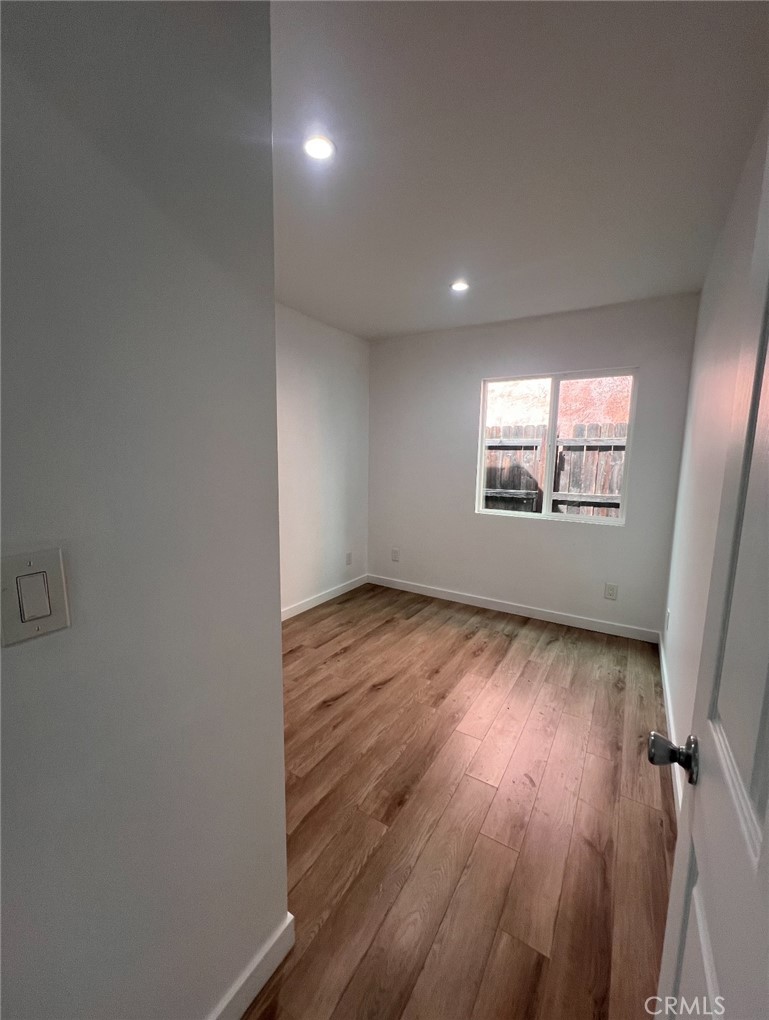 1207 East 23rd Street, Unit 1/2 Los Angeles, CA 90011 - Photo 4 of 8 an empty room with wooden floor and windows