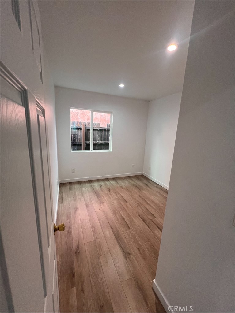 1207 East 23rd Street, Unit 1/2 Los Angeles, CA 90011 - Photo 6 of 8 an empty room with wooden floor and windows