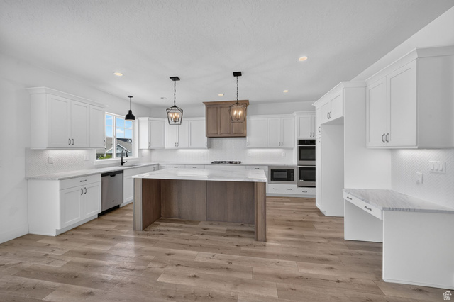 1002 West Temple Rim Lane Payson, UT 84651 - Photo 18 of 68 Spacious kitchen featuring an expansive island with a stone-finish countertop, white shaker-style cabinetry, stainless steel appliances, wood-finish flooring, and a decorative range hood