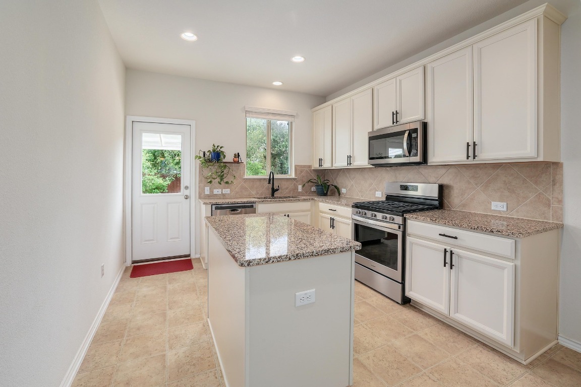 1924 Cliffbrake Way Georgetown, TX 78626 - Photo 11 of 27 a kitchen with stainless steel appliances granite countertop a sink a stove a refrigerator and white cabinets