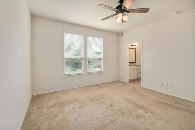 an empty room with windows and fan