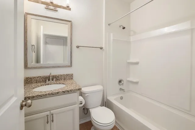 a bathroom with a granite countertop toilet a sink and a bathtub