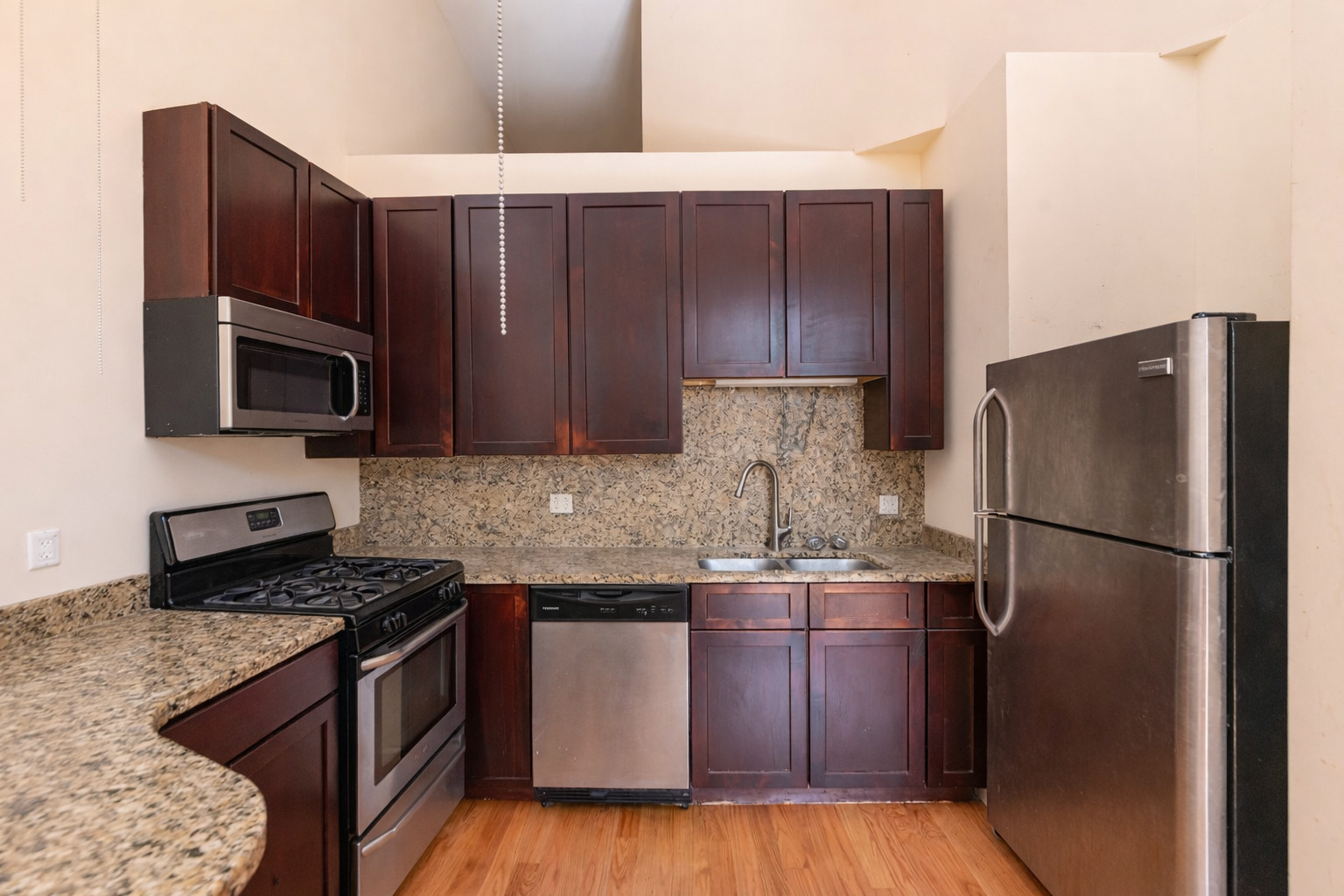 2415 West 24th Street, Unit 6 Chicago, IL 60608 - Photo 2 of 12 a kitchen with kitchen island granite countertop wooden cabinets stainless steel appliances and a counter space