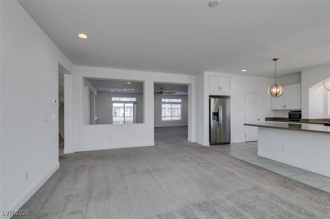 6335 Rock Strm Lane Las Vegas, NV 89141 - Photo 34 of 61 Unfurnished living room featuring light colored carpet, ceiling fan, recessed lighting, light tile patterned floors, and a chandelier