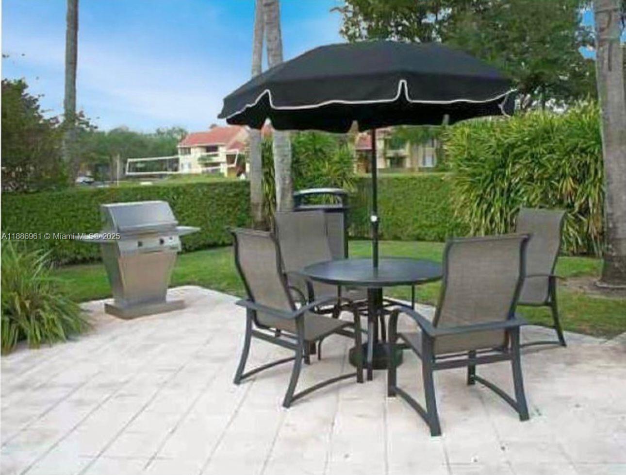 711 Lyons Road, Unit 14107 Coconut Creek, FL 33063 - Photo 24 of 24 a view of a patio with table and chairs under an umbrella