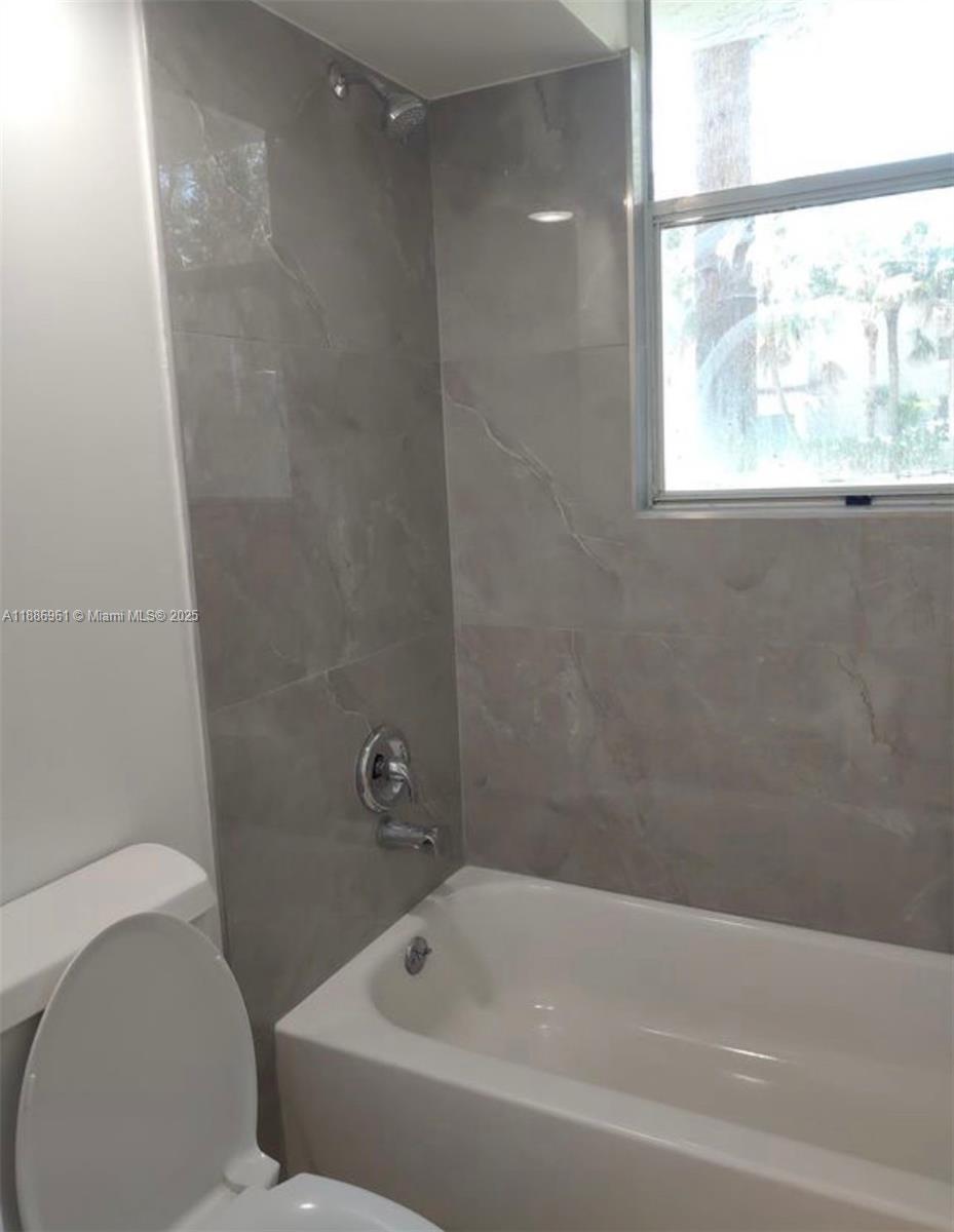 711 Lyons Road, Unit 14107 Coconut Creek, FL 33063 - Photo 4 of 24 a bathroom with a bathtub and window