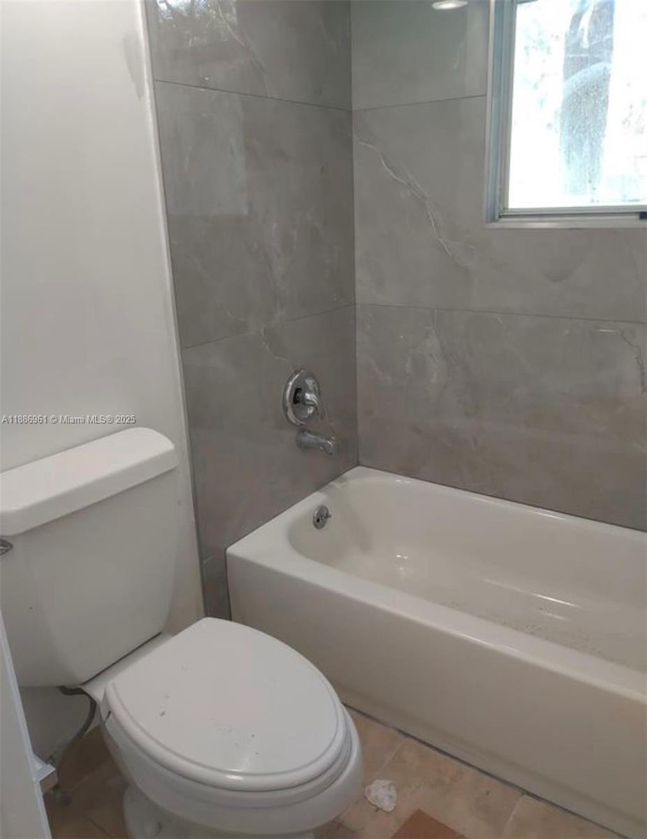 711 Lyons Road, Unit 14107 Coconut Creek, FL 33063 - Photo 5 of 24 a white toilet and tub sitting next to a window