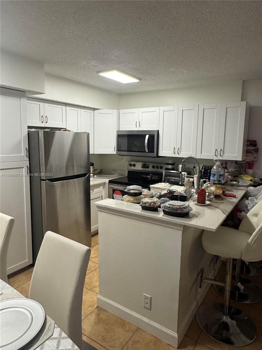 711 Lyons Road, Unit 14107 Coconut Creek, FL 33063 - Photo 7 of 24 a kitchen with stainless steel appliances a refrigerator stove a sink and a microwave