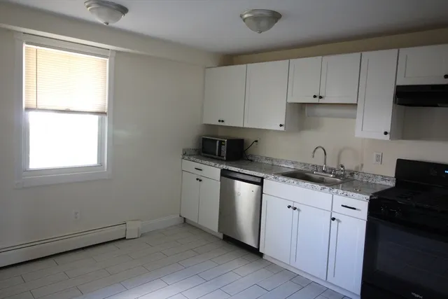a kitchen with granite countertop white cabinets sink and stainless steel appliances