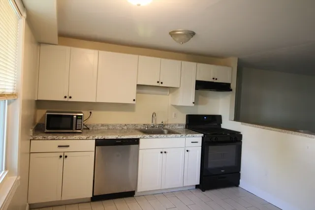 a kitchen with white cabinets and appliances