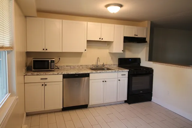 a kitchen with granite countertop white cabinets and stainless steel appliances