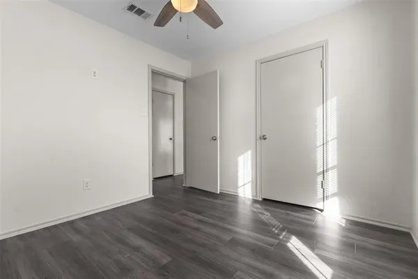 an empty room with wooden floor and ceiling fan