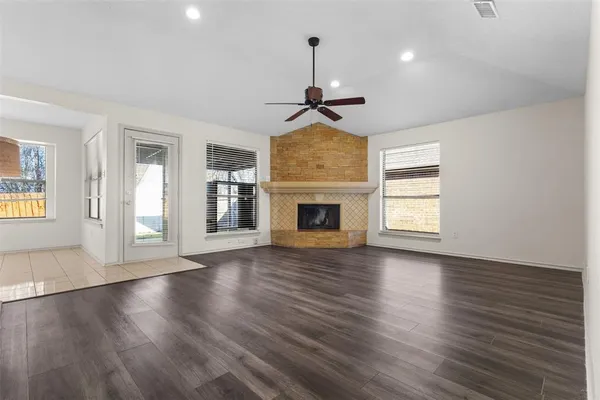 an empty room with wooden floor fireplace and windows