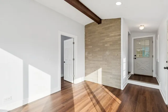 a view of a livingroom with wooden floor and a hallway