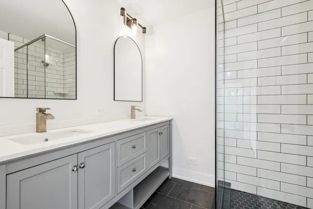 a bathroom with a double vanity sink a mirror and a shower