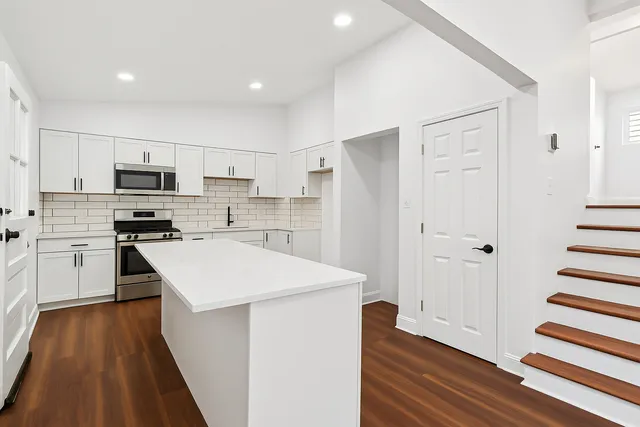 a kitchen with a refrigerator a stove top oven and wooden floor