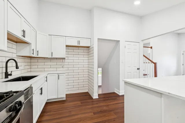 a kitchen with a sink cabinets stainless steel appliances and wooden floor