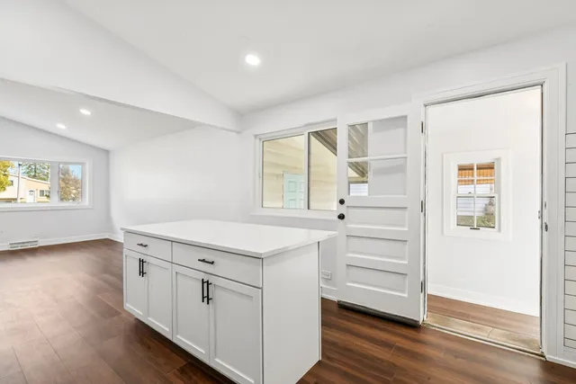 a kitchen with white cabinets and wooden floor
