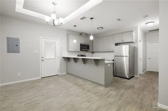 a view of a kitchen with stainless steel appliances refrigerator stove microwave and cabinets