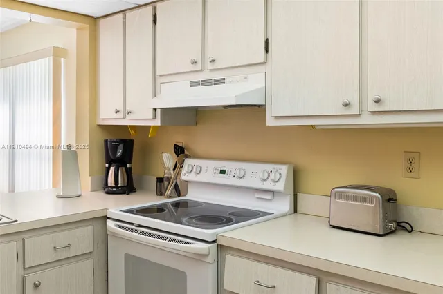 a kitchen with white cabinets and sink