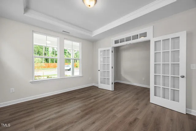 an empty room with wooden floor closet and windows