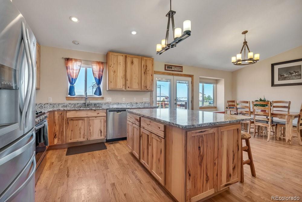 24535 County Road 5 Elbert, CO 80106 - Photo 4 of 45 a kitchen with stainless steel appliances granite countertop a stove top oven a sink dishwasher a dining table and chairs with wooden floor