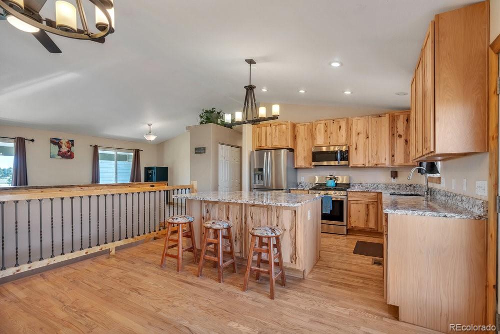 24535 County Road 5 Elbert, CO 80106 - Photo 6 of 45 a kitchen with stainless steel appliances kitchen island granite countertop a table chairs and a refrigerator