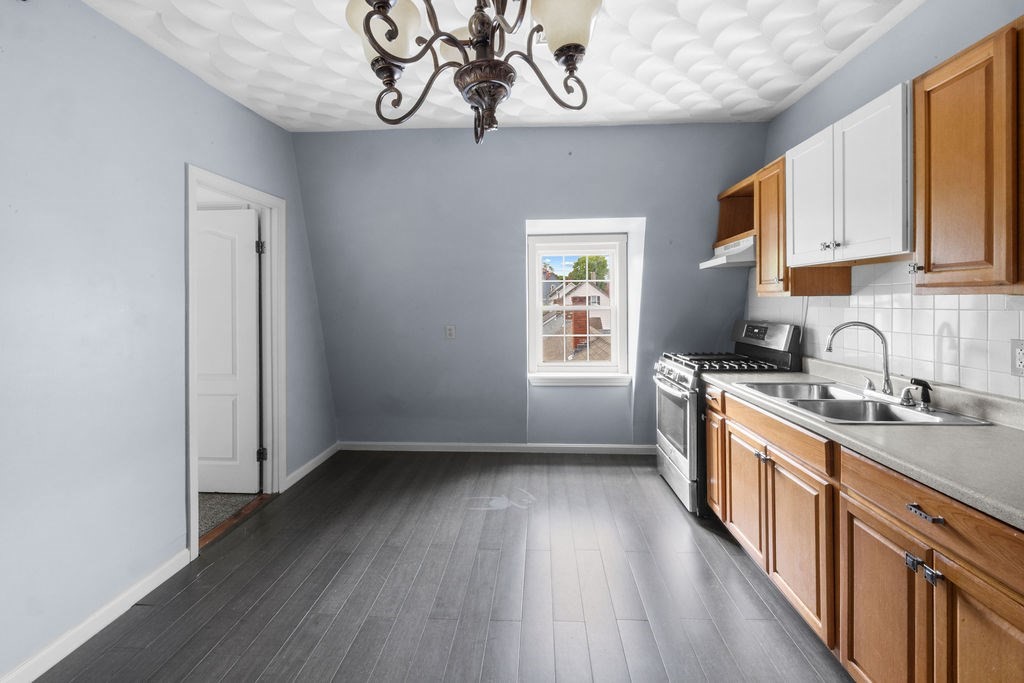 186 John Street Fall River, MA 02721 - Photo 16 of 38 a kitchen with stainless steel appliances granite countertop a stove a sink dishwasher and white cabinets with wooden floor