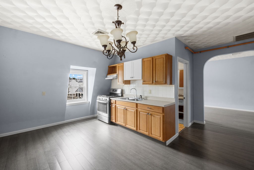 186 John Street Fall River, MA 02721 - Photo 20 of 38 a kitchen with stainless steel appliances granite countertop a sink dishwasher a stove a dining table and chairs with wooden floor