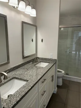 a bathroom with a granite countertop sink a toilet and a mirror