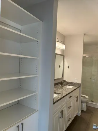 a bathroom with a granite countertop sink a toilet and a mirror