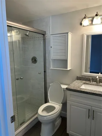 a bathroom with a granite countertop sink toilet and shower