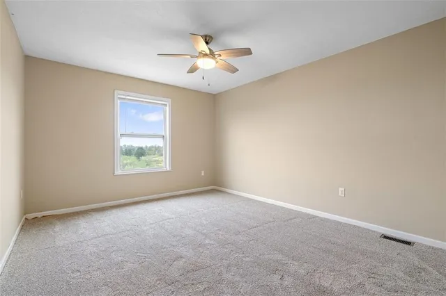 an empty room with a chandelier fan and windows