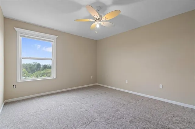an empty room with a chandelier fan and windows