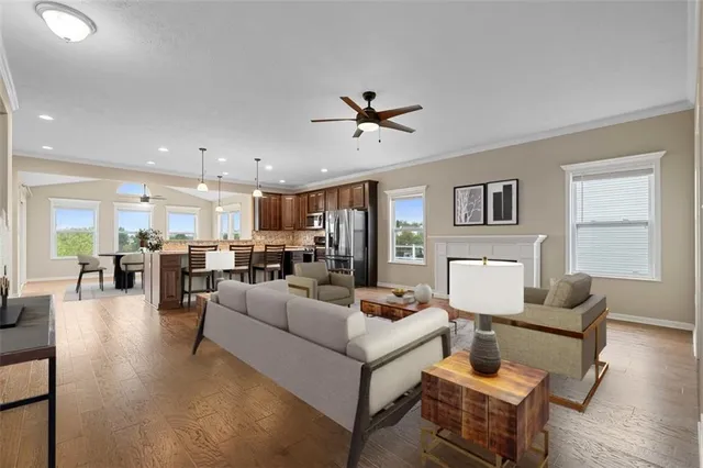 a living room with furniture kitchen view and a wooden floor