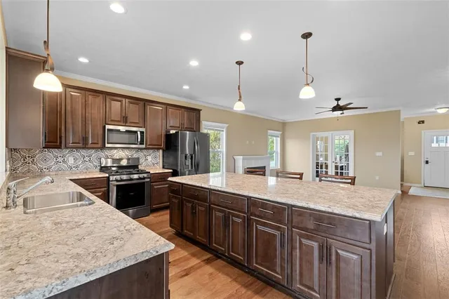 a kitchen with stainless steel appliances granite countertop a sink a stove and a wooden floors