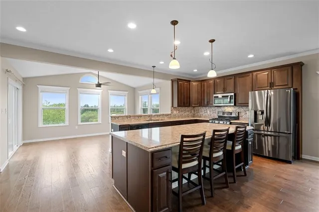 a kitchen with stainless steel appliances granite countertop a table chairs sink refrigerator and microwave