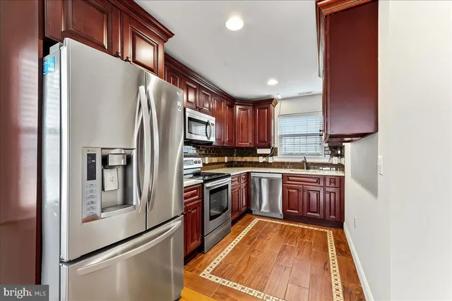 a kitchen with stainless steel appliances granite countertop a refrigerator a stove and a sink