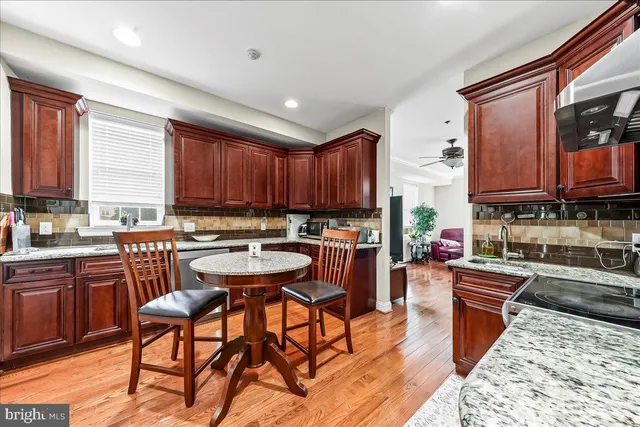 a kitchen with stainless steel appliances granite countertop wooden cabinets a stove top oven a sink and dishwasher with wooden floor