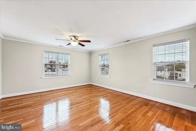 a view of an empty room with a window and wooden floor