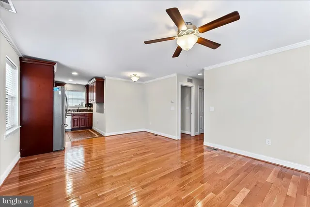 a view of empty room with wooden floor and ceiling fan