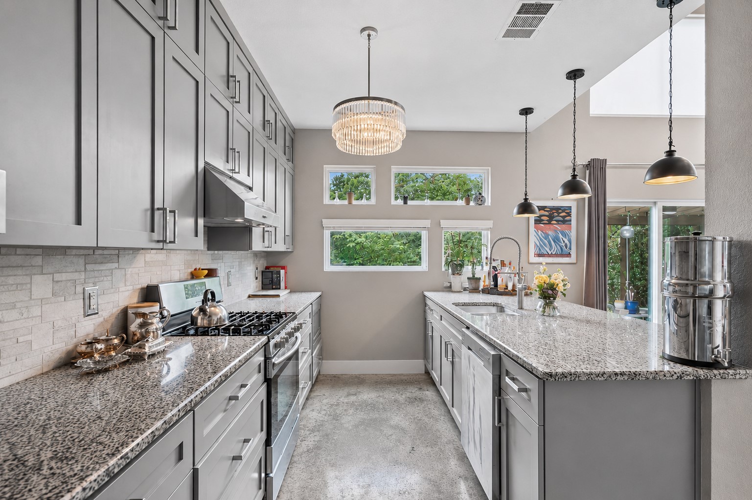 1800 Webberville Road, Unit B Austin, TX 78721 - Photo 13 of 30 Contemporary kitchen featuring extensive gray shaker cabinetry, speckled granite countertops, a tiled backsplash, and stainless steel appliances